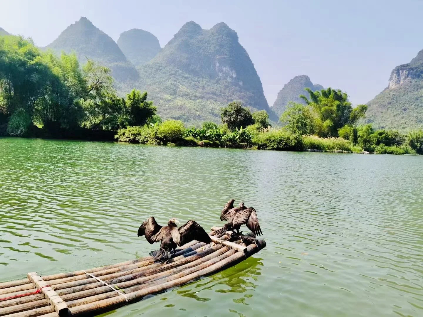 Traditional wooden-roofed minority village surrounded by misty green mountains in rural China