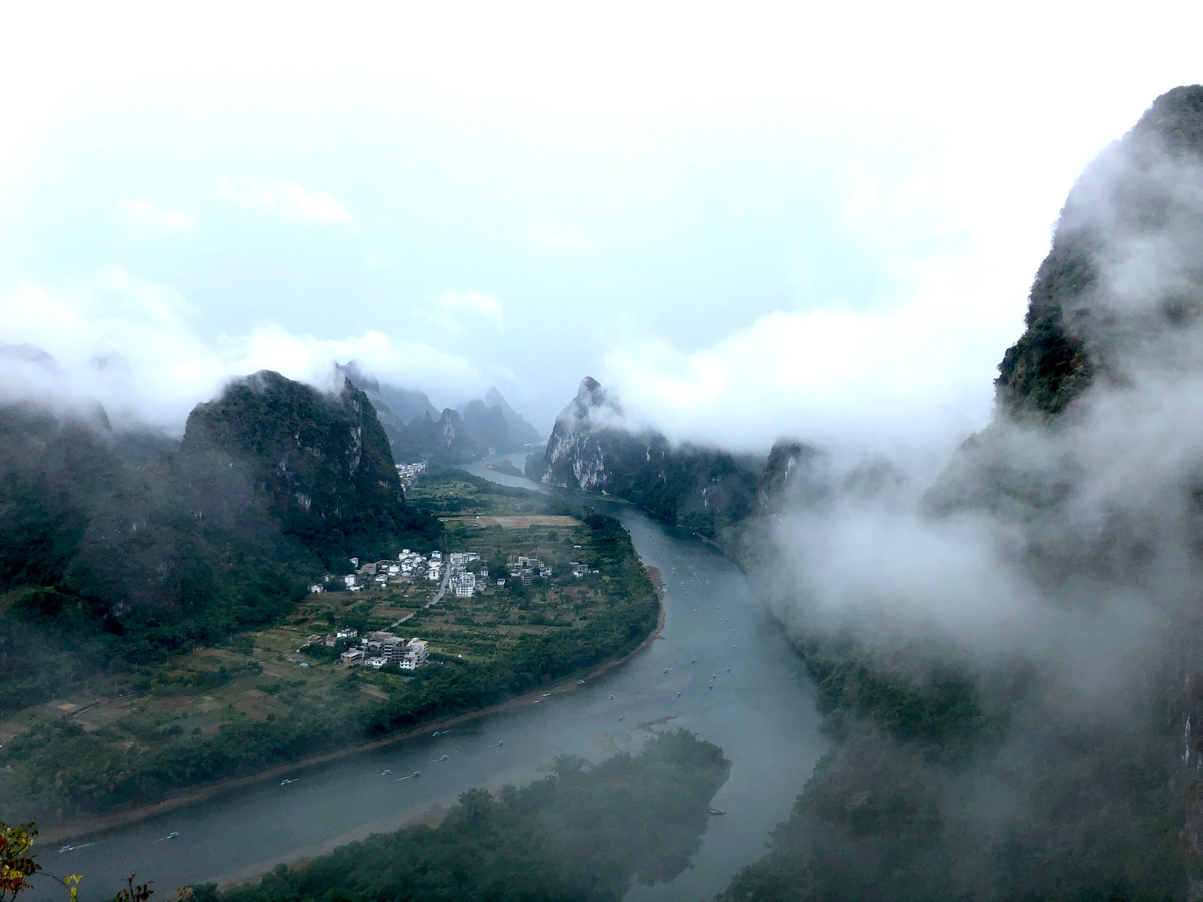 Group of hikers at a mountain viewpoint with a rainbow arcing over the terraced valley in China