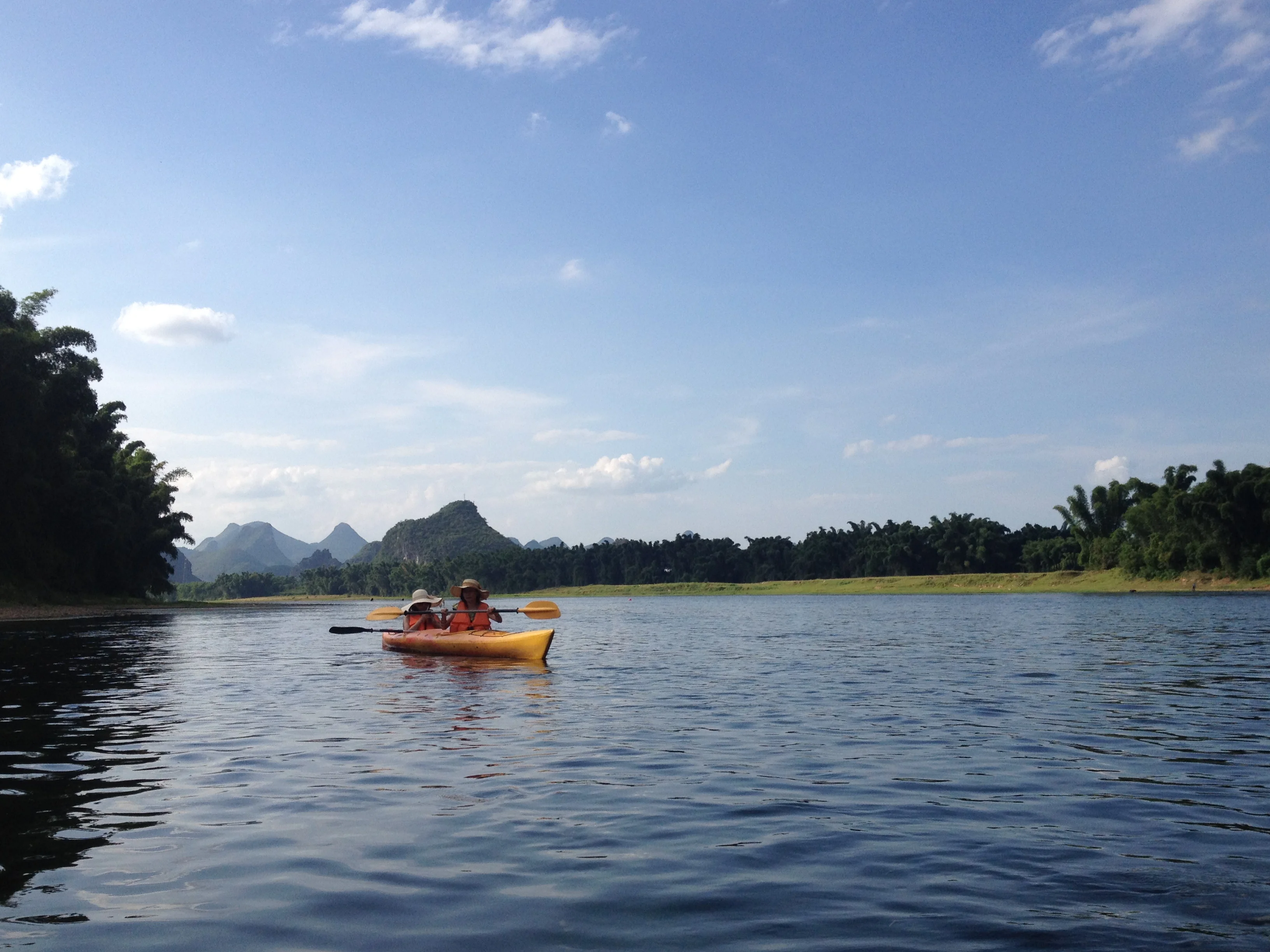 Group of participants swimming and paddling in a river with karst peaks rising in the background, China