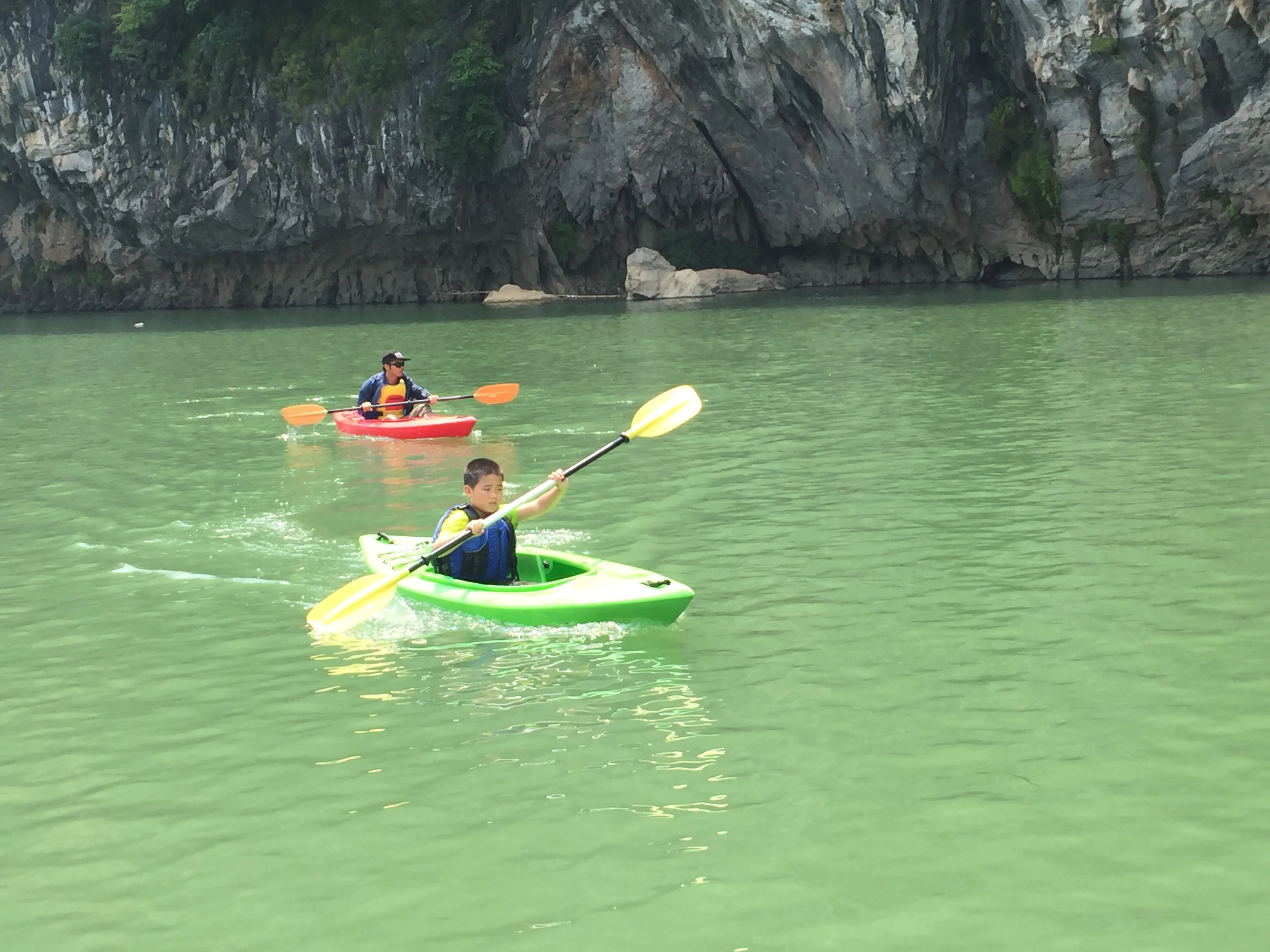 Family group with children on the water, green mountains and a bridge in the background, China