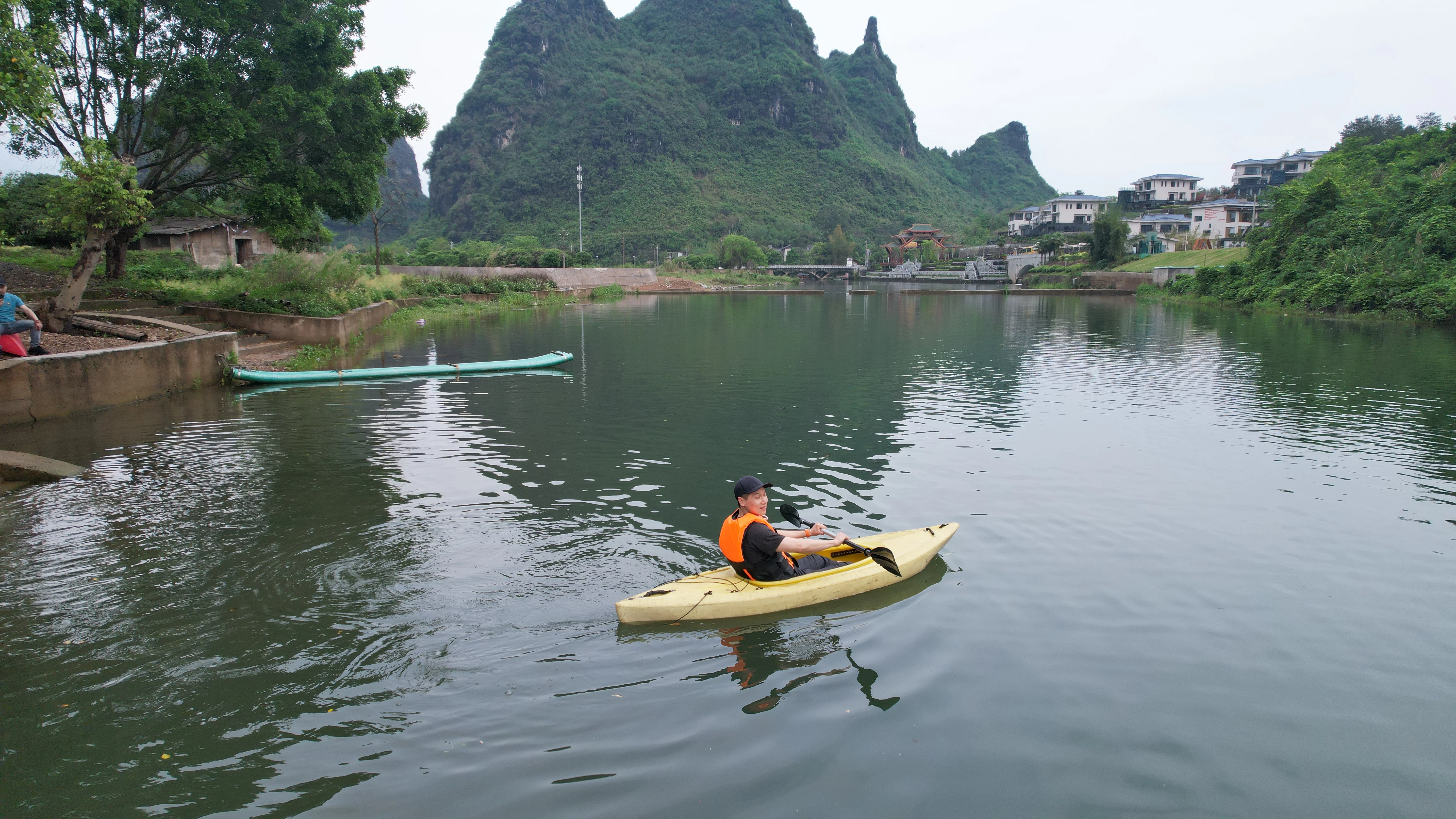 Group in life jackets on a calm river with lush karst mountains reflected in the water, China