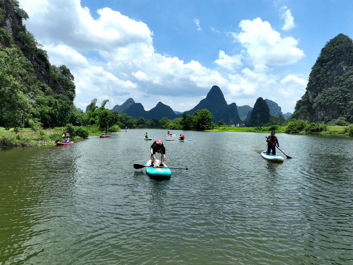 Aerial view of participants in life jackets on paddleboards on a natural jungle river, China