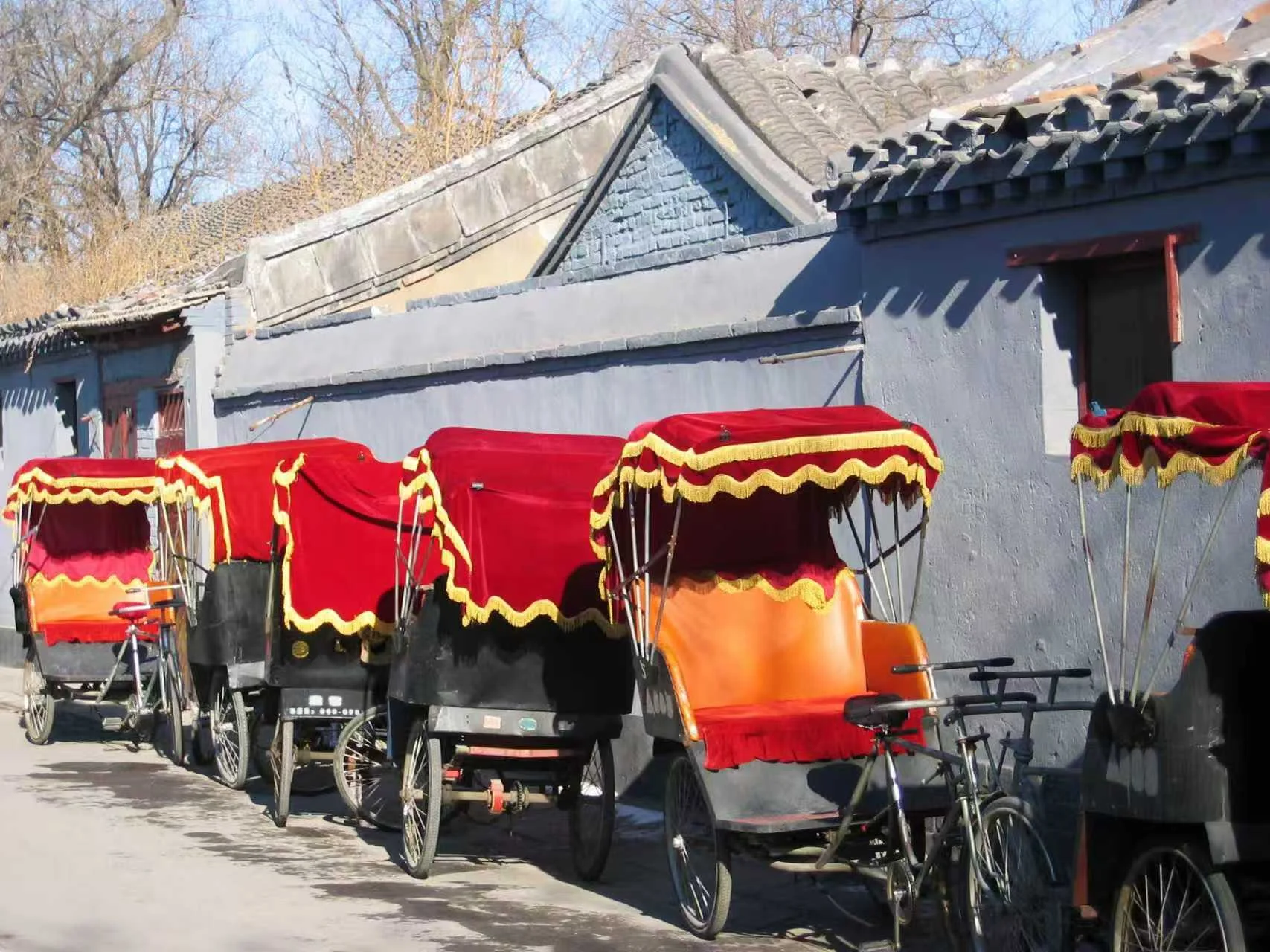 Traditional red rickshaws parked in a Beijing hutong alley
