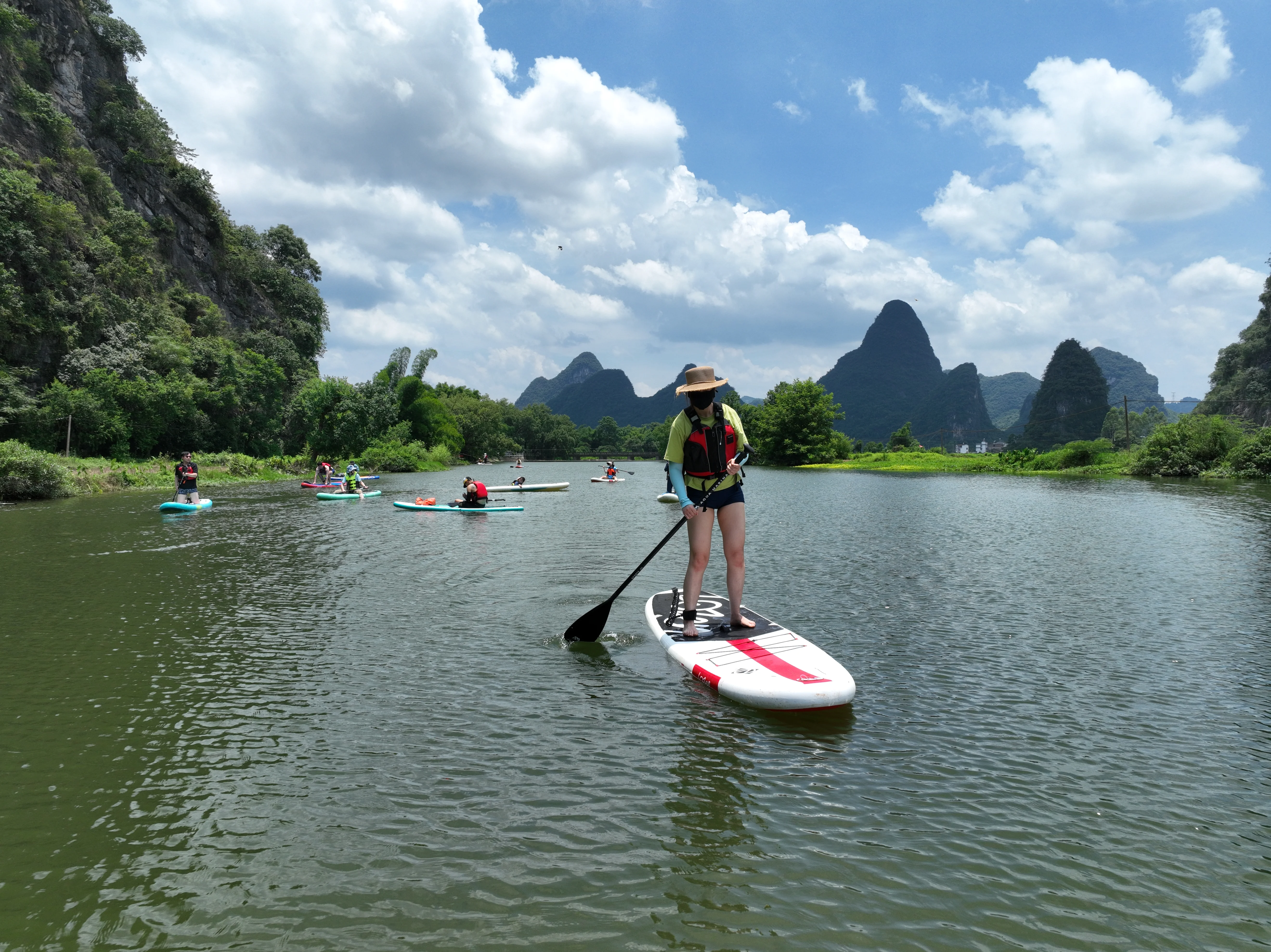 Paddler drifting past reflected karst peaks at golden hour, Yangshuo
